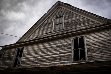 Abandoned dilapidated creepy wooden house boarded up attic window