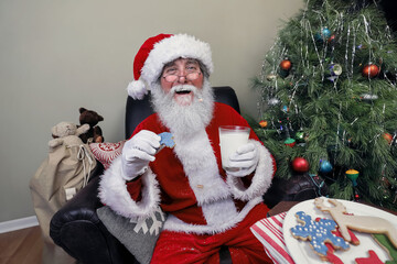 Santa Claus eating cookies and drinking milk left out on Christmas Eve