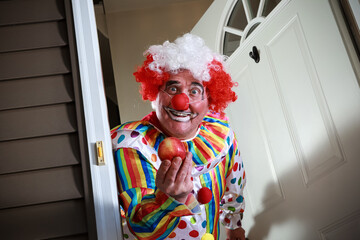 Awkward man dressed in a clown costume handing out apples for trick or treat