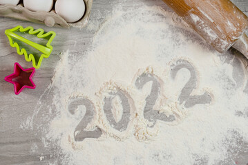 Christmas New Year background on the kitchen table. Flour, rolling pin, eggs and baking dish. Christmas food preparation concept.