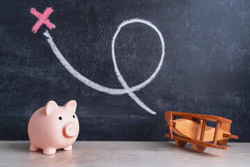 A piggy bank and a wooden biplane airplane on a chalk board background. Chalk drawing of loops and...
