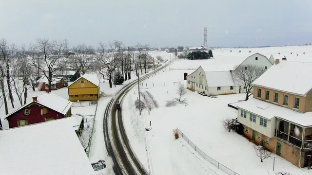 Amish buggy on snow covered road during winter snowstorm. Aerial in Lancaster County Pennsylvania USA.