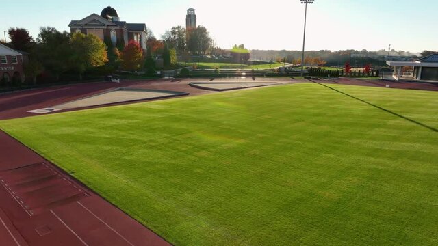 Aerial Of Track And Field Outside At College University In USA During Golden Hour Light.