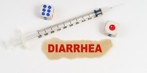 On a white surface lies a syringe, dice and a piece of paper with the inscription - DIARRHEA