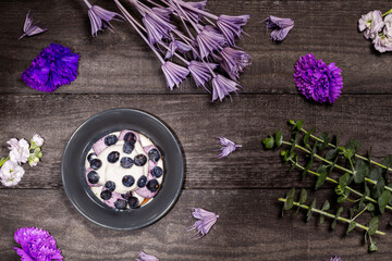 Blueberry Graham Cheesecake topped with fresh berries, on a dark wood background with purple...