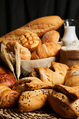 Close up of bread basket with milk, flour and ears of wheat on the table. Food and bakery concept. Vertical photo.
