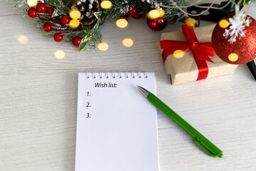 notepad with pen on wooden background with gift and ckristmas light and decoration