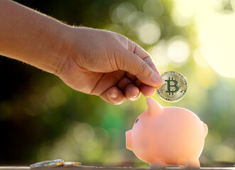Hand saving bitcoins cryptocurrency in to a piggy bank