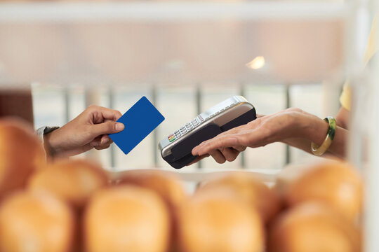Hands of customer swiping credit card to pay for order