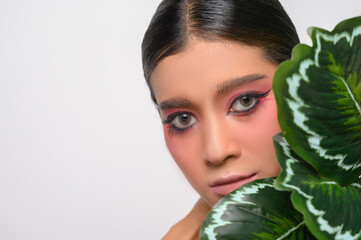 The woman put on pink makeup and decorated with leaves.