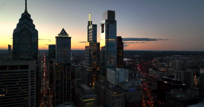 Silhouettes of office building towers at sunset. Traffic in street below. Aerial slo-mo view, dramatic silhouette.