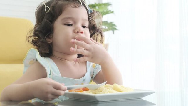 Little girl eating spaghetti noodles deliciously,pasta italian food and vegan.