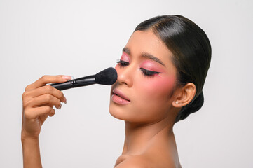 woman wearing pink makeup and holding a blush brush