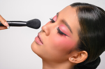 woman wearing pink makeup and holding a blush brush