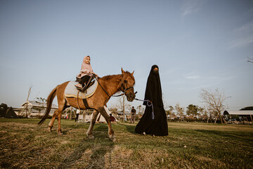 Muslim girl practicing horseback riding in childcare center