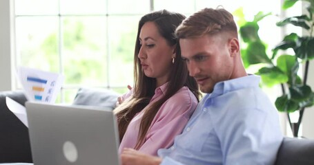 Millennial Caucasian lovely lover young couple husband and wife sitting cuddling hugging discussing talking together reviewing taxes expenses and bills payment paper documents with laptop computer. - Powered by Adobe