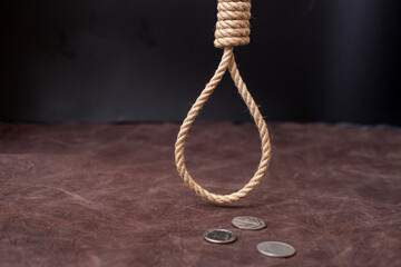 hangman's noose hanging over 3 silver coins on brown leather background