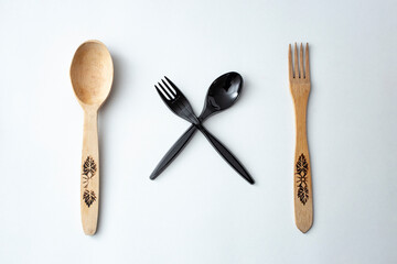plastic versus wood cutlery on white background