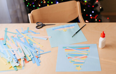 Creating Christmas card. Colored paper, glue, example of ready-made card