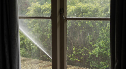 Jet of Water Spraying House Seen Through Window - Concept Cleaning Exterior Windows and Walls of House