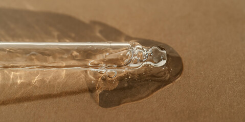 The texture of serum or oil with a pipette on a beige background.