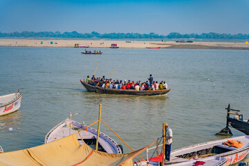 Fototapeta premium Boats transport pilgrims across the sacred river Ganges, Varanasi is the most popular pilgrim place in India
