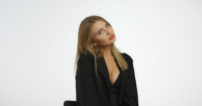 Beautiful woman in a black shirt with long blond hair looks offendedly into the camera. Model caucasian girl in the studio on a white background