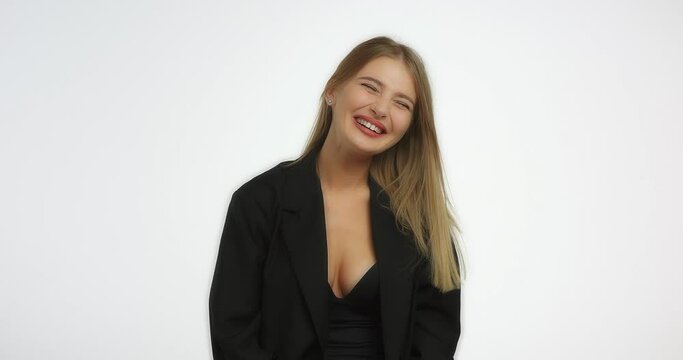 Beautiful young woman with long blond hair laughs. Young caucasian woman in a black shirt smiling in the studio on a white background.