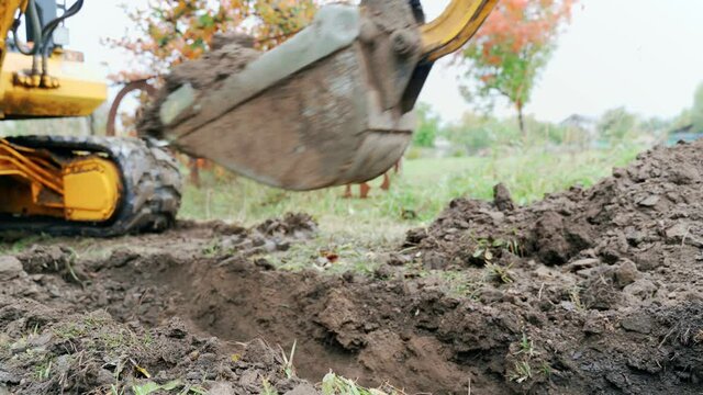 An excavator digs a trench to lay a pipeline. A small excavator is doing earthworks.