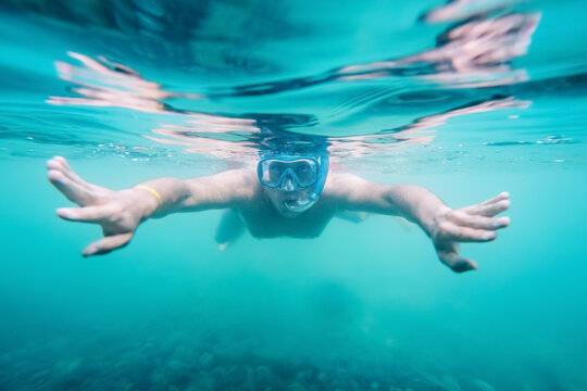 A young and happy man enjoys snorkeling underwater at an amateur level. Photo underwater with a narrow depth of field