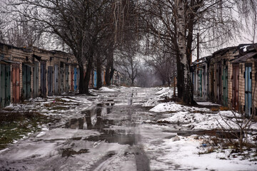 puddle of melted white snow on a cloudy spring day. Garage society, cooperative society. a street between brick garages. ukraine, Dnipropetrovsk region. 22.01.2021.