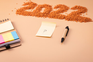 Number 2022, notepad, pen and sheet of paper with a question mark. The figurine is made of bright orange shiny beads. Signs and symbols of the new year for copy space. Festive mockup.