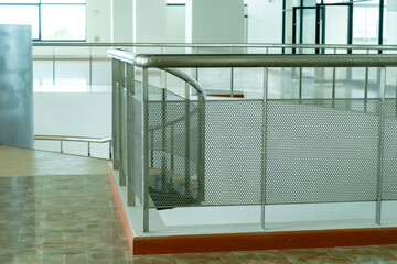 The railings in a building are made of silver stainless steel for people to walk and grab and for safety to prevent people from falling to the bottom.