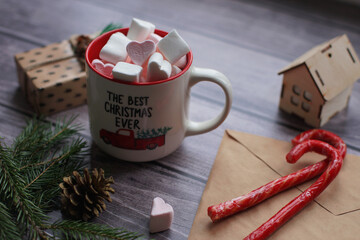 Cocoa with marshmallows, caramel candies, toys on a wooden photophone.