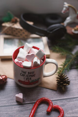 Cocoa with marshmallows, caramel candies, toys on a wooden photophone.