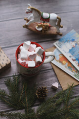 Cocoa with marshmallows, caramel candies, toys on a wooden photophone.