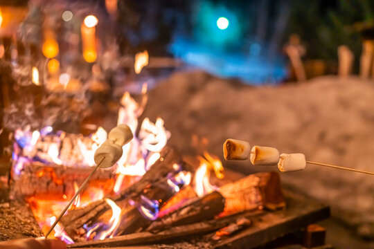 Winter fire pit campfire people roasting marshmallows over firepit at outdoor after ski resort. Family vacation.