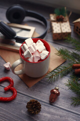 Cocoa with marshmallows, caramel candies, toys on a wooden photophone.