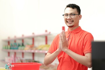 Smiling young man cashier with a welcome greeting hand gesture