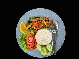 Fried chicken basil with rice decorated with tomato and cucumber on isolated black background