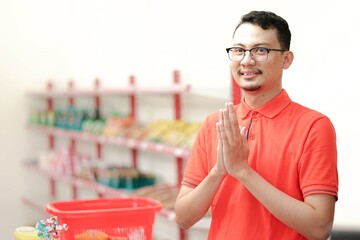 Smiling young man cashier with a welcome greeting hand gesture