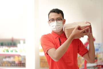 an employee of a supermarket wear uniform and medical mask lifting inventory items