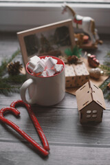 Cocoa with marshmallows, caramel candies, toys on a wooden photophone.