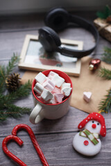 Cocoa with marshmallows, caramel candies, toys on a wooden photophone.