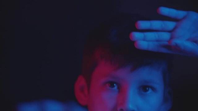 A little boy doing taekwondo in the dark with neon lighting
