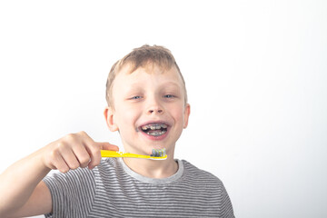 Caucasian boy brushes his teeth with black toothpaste with charcoal