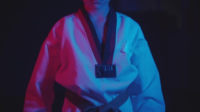 A little boy doing martial arts in the dark with neon lighting - standing in the position