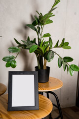 Black design room with mock up photo frame,tropical leaf and office accessories. Modern and stylish black interior.