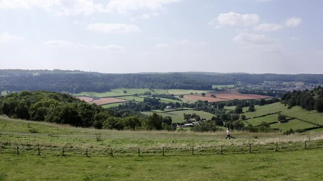 AERIAL - People walk their dog on a hill near Uley, Cotswolds, England, truck right