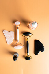 Top view of   stone rollers and Gua Sha tools,  natural serums and cream on beige background